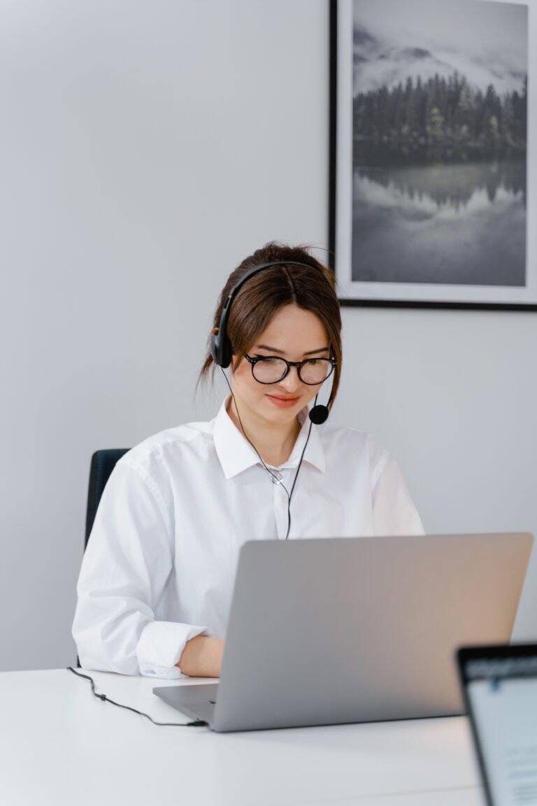Professional woman providing customer support using a laptop and headset in a modern office.